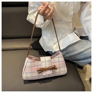 Detail of pink and blue plaid baguette bag with brown leather bow and strap