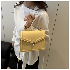 Detailed view of yellow structured crossbody bag with gold-tone twist lock and fine stitching