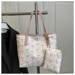 Detail of white tote and pouch with pink bow prints hanging on a metal rack