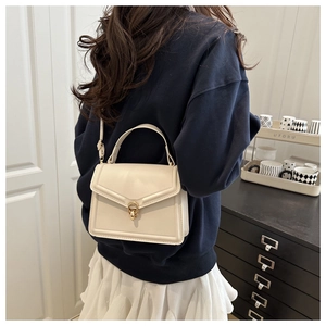 Detail of cream leather shoulder bag with gold twist lock and adjustable crossbody strap