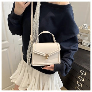 Detail of cream square crossbody bag with gold twist lock and elegant lace scarf handle