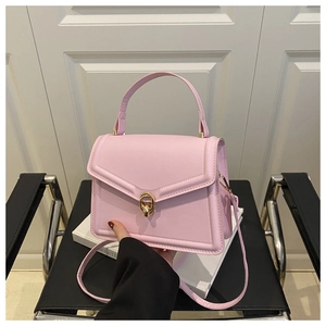 Detail of light pink crossbody bag featuring a golden twist lock and matte leather texture