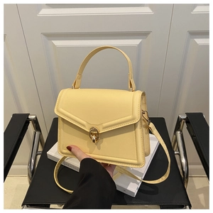 Detail of light yellow handbag featuring golden twist lock and smooth synthetic leather