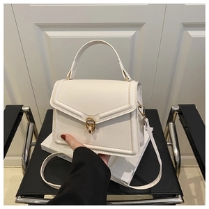 Detail of white leather handbag with golden ring buckle lock on minimalist chair