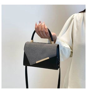 Detail of elegant black and grey crossbody bag with gold metal trim and textured flap