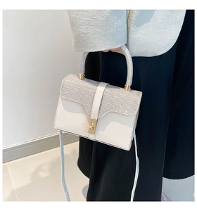 Detail der weißen Fashion-Umhängetasche mit silbernen Akzenten und goldenem Verschluss
