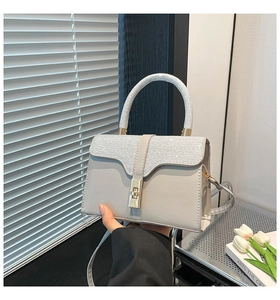 Detail of grey crossbody bag featuring rhinestone handle and gold metal twist lock