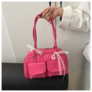 Detail of rose pink faux leather bag with white lace bow and twin front pockets
