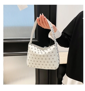 Close-up of white lychee leather bag with silver metal rivets and buckle details