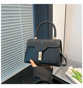 Macro shot of black matte leather handbag with glitter flap and golden swivel lock