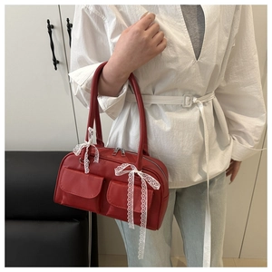 Detail of red leather shoulder bag with white lace ribbons and double front pockets