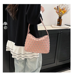 Detail of pink leather shoulder bag featuring silver metal rivets and grainy texture