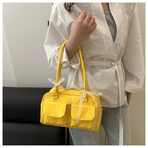 Detail of yellow baguette bag featuring double front pockets and lace bow accents