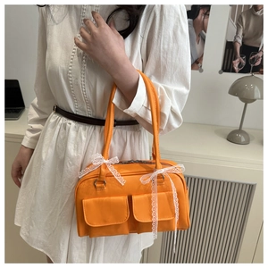 Detailed macro view of an orange leather bag featuring a cute white lace bow on the handle