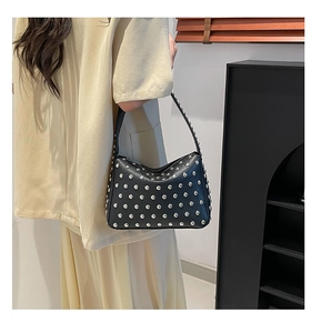 Detailed view of black leather hobo bag with silver metallic studs worn by a model