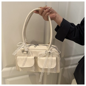 Detail of cream pillow bag with lace bows on front pockets held by hand