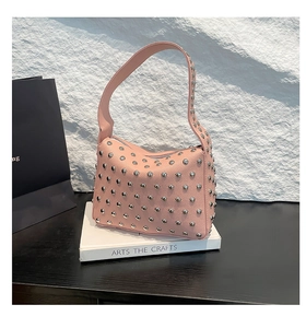 Close-up of pink rivet leather hobo bag on art books with silver studs and metal details