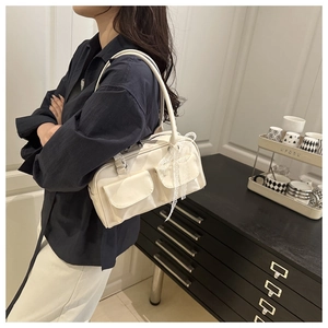 Detail of cream PU leather Boston bag with front pockets and white lace ribbons