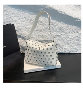 Detail of white lychee leather shoulder bag with silver studs and wide strap