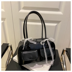 Close-up of black PU leather pillow bag featuring white lace bows and double front pockets
