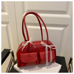 Macro shot of red vintage Boston bag with white lace bows and glossy PU finish