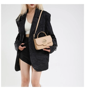Close-up of beige crossbody bag featuring a gold M-letter logo and leather texture