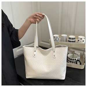 Detail of woven texture on a white tote bag with silver rivets and dual slim straps
