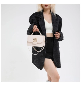 Detail of cream flap square bag with golden M metal buckle and top handle