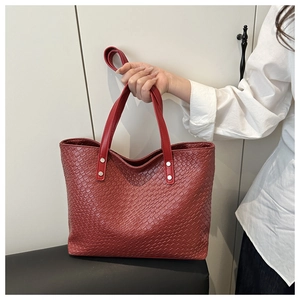 Detail of red large tote bag featuring woven texture and silver rivet hardware handles