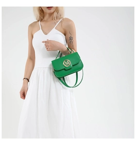 Detail of vibrant green handbag with gold M-buckle worn on a white dress