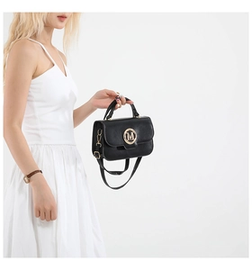 Detail view of the elegant black square bag with gold M buckle on white dress model