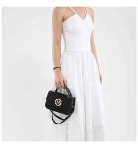 Detail of black leather handbag featuring a golden M logo and a slender shoulder strap