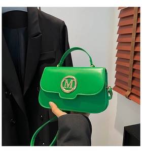 Detailed macro view of the vibrant green crossbody bag with a golden M letter buckle