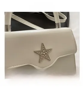 Détail d'un sac en cuir blanc avec un ornement étoile en argent et strass brillants