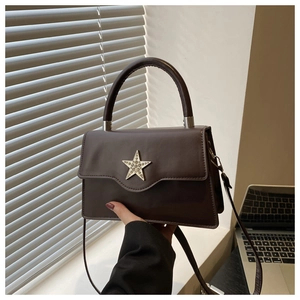 Détail d'un sac bandoulière marron foncé avec boucle en étoile dorée étincelante