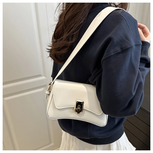 Close-up of a white minimalist shoulder bag with a stylish black and gold metal lock
