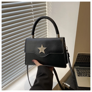 Détail d'un sac bandoulière en cuir noir avec boucle étoile sertie de strass