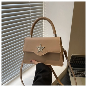 Détail du sac bandoulière beige avec boucle étoile en strass et rabat au design ondulé