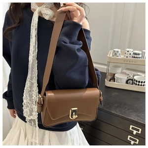 Close-up of brown faux leather shoulder bag with golden metallic lock and wide strap