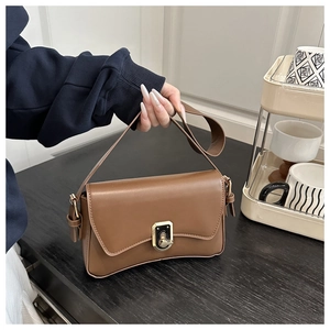 Close-up of brown faux leather handbag with golden twist lock and adjustable strap
