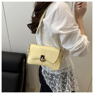 Detail of cream leather shoulder bag with unique curved base and dual-tone metal buckle