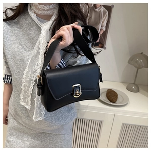 Close-up of black leather crossbody bag featuring a golden twist-lock and elegant details