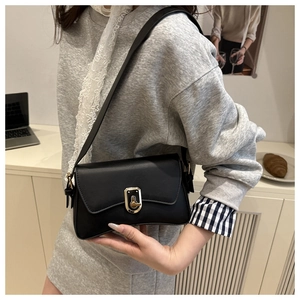 Close-up of elegant black leather crossbody bag with a golden metal twist-lock buckle