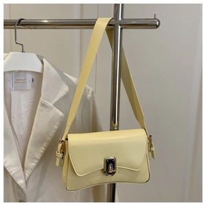 Detail of a creamy yellow crossbody bag with a gold twist lock on a minimalist rack