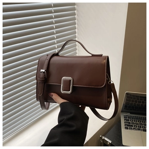 Close-up of retro dark brown leather handbag with silver metallic buckle on a desk