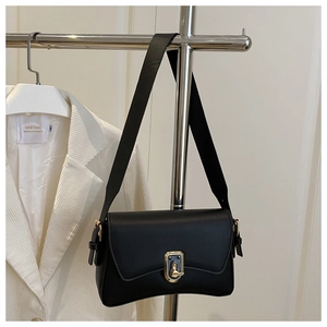 Detail of minimalist black leather shoulder bag with gold clasp and unique curved bottom