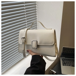 Close-up of cream square handbag showing silver buckle and fine leather texture