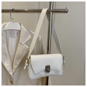 Close-up of white leather saddle shoulder bag with vintage twist lock on a display rack