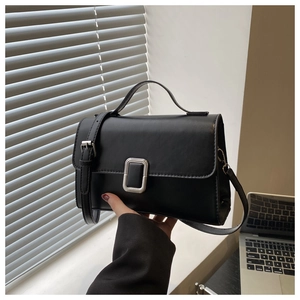 Detailed view of black leather handbag with silver square clasp and adjustable strap
