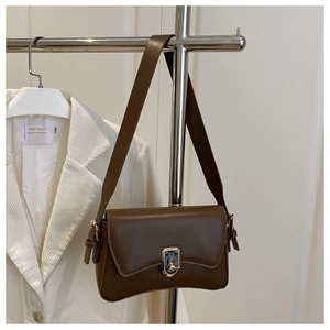 Detail view of coffee brown leather bag with vintage metal buckle and broad strap
